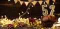Number 57 golden festive burning candles in a cake, wooden holiday background. fifty-seven years since the birth. the Royalty Free Stock Photo