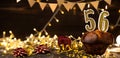 Number 56 golden festive burning candles in a cake, wooden holiday background. fifty-six years since the birth. the Royalty Free Stock Photo