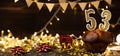 Number 53 golden festive burning candles in a cake, wooden holiday background. fifty-three years since the birth. the Royalty Free Stock Photo