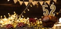 Number 52 golden festive burning candles in a cake, wooden holiday background. fifty-two years since the birth. the Royalty Free Stock Photo