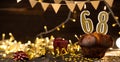 Number 68 golden festive burning candles in a cake, wooden holiday background. sixty-eight years since the birth. the