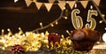 Number 65 golden festive burning candles in a cake, wooden holiday background. sixty-five years since the birth. the Royalty Free Stock Photo