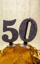 Number 50 happy birthday celebration candle. Candles on a homemade cake. Silver background Royalty Free Stock Photo