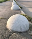 A number of heavy hemispheres of concrete on the sidewalk.