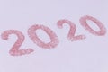 2020 number made of pink sand scattered on white background