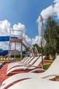 A number of many light loungers near the pool with a slide