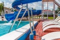 A number of many light loungers near the pool with a slide