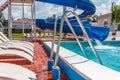 A number of many light loungers near the pool with a slide