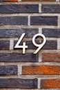 Number 49 metal house number on brick wall