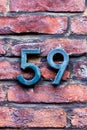 Number 59 metal house number on brick wall