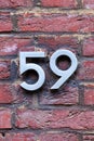 Number 59 metal house number on brick wall