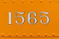 Number 1565 on orange panel with rivets Royalty Free Stock Photo