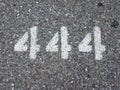 The number 444 painted on black asphalt