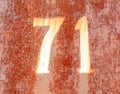 The number 71 on a rusty metal fence