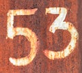 The number 53 on a rusty metal fence