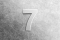 Number seven embossed on a scratched metal background Royalty Free Stock Photo