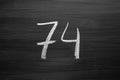 Number seventy four enumeration written with a chalk on the blackboard