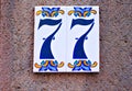 Number 77, seventy-seven, blue digits on floral tiles.