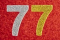 Number seventy-seven yellow silver color over a red background.