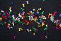 Number 70 with shiny party hat star glitter on black background