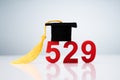 529 Number Showing With Miniature Of Graduation Hat Over Desk