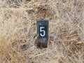 Number 5 on sign on ground with grasses Royalty Free Stock Photo