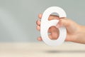 Number six in hand. Hand holding white number 6 on blurred background with copy space. Concept with number six. Birthday Royalty Free Stock Photo