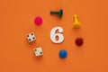 Number six in white with pieces and gambling dice - Orange eva rubber background Royalty Free Stock Photo