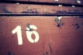 Number sixteen painted on an old wooden seat.