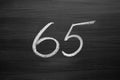 Number sixty five enumeration written with a chalk on the blackboard