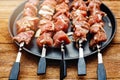 A number of skewers with meat laid out in a black plate. Close-up of mouth-watering pieces of beef ready to fry. Meat dish. Top vi