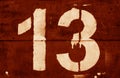 Number 13 in stencil on metal wall in orange tone