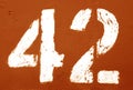 Number 42 in stencil on rusty metal wall in orange tone