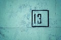 Number 13 is stenciled in black frame on green concrete wall, copy space