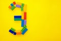 The number three from the children`s multi-colored constructor on a yellow background