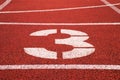 Number three. White track number on red rubber racetrack, texture of racetracks in stadium Royalty Free Stock Photo