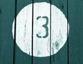 Number three on wooden cyan toned wall.