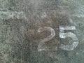 Number 25 Twenty five in white painted on the gray concrete wall or surface of street with copy space Royalty Free Stock Photo