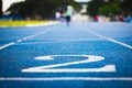 Number two on the start of a running track .Blue treadmill with different numbers and white lines.Selective focus on Number. Royalty Free Stock Photo