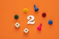 Number two in white with pieces and gambling dice - Orange eva rubber background Royalty Free Stock Photo