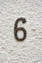 Isolated authentic number 6 wrought iron hanging symbol on whitewashed harled stone wall Royalty Free Stock Photo