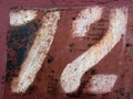 Number 72 white digit painted on rust weathered red brown metal surface. Royalty Free Stock Photo