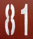 Number 81 white digit painted on rusty weathered red metal surface