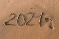 Number 2021 is written on the sand at sea.. Two thousand twenty one.a footprint in the sand