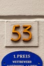 Number 53 yellow house number on white wall