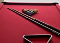 Numbered Billiard balls on a red pool table with two cues and a black ball rack
