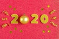 2020 numbers decorated with gold sequins, stars, ribbon on shiny coral red background