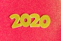 2020 numbers decorated with gold sequins, stars, ribbon on shiny coral red background