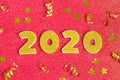 2020 numbers decorated with gold sequins, stars, ribbon on shiny coral red background