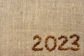 Numbers 2023 are made from coffee beans on fabric with burlap texture. View from above. Place for text. Royalty Free Stock Photo